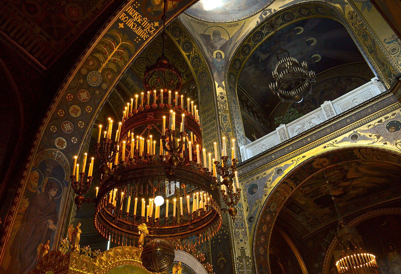 Ornate gold chandelier under a painted ceiling
