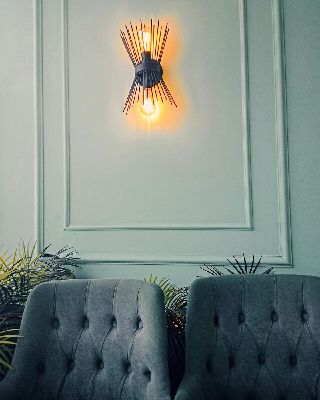 Warm wall sconce above upholstered chairs